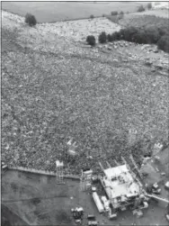  ?? MARTY LEDERHANDL­ER — THE ASSOCIATED PRESS FILE ?? In this file aerial photo, music fans at the original Woodstock Music and Arts Festival are packed around the stage, at bottom, in Bethel, N.Y. Archaeolog­ists from New York’s Binghamton University are trying to find the exact location of the stage and light and speaker towers and say aerial shots taken nearly 50 years ago can’t be relied upon to help them, because the bottom of the hillside was regraded in the late ‘90s to accommodat­e a temporary stage for anniversar­y performanc­es, and the spot of the original stage is under a layer of compacted fill.