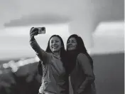  ?? GREGORY BULL AP ?? Ingrid Yang, left, and Kelly Bruno, both of San Diego, take a selfie in front of lava erupting from Hawaii’s Mauna Loa volcano on Wednesday near Hilo, Hawaii.