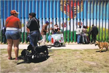  ?? JOHN MOORE GETTY IMAGES FILE ?? Mexicans gather at the Tijuana side of the U.s.-mexico border fence that straddles Friendship Park in May 2016. The park on has been closed since early last year because of the pandemic.