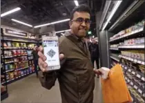  ?? ELAINE THOMPSON, THE ASSOCIATED PRESS ?? Amazon employee Krishna Iyer shows off an Amazon Go app as he shops in the Amazon Go store in Seattle on Monday.