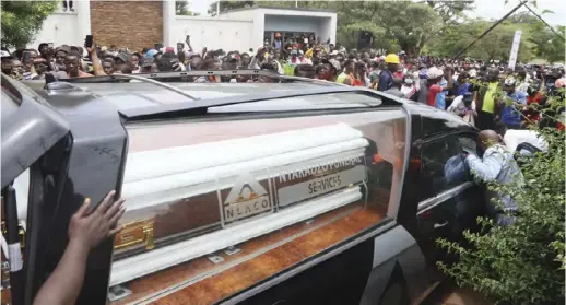  ??  ?? Fans jostle around the hearse carrying Soul Jah Love's casket to bid farewell