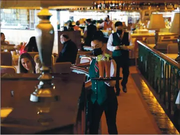  ?? ARIC CRABB — STAFF PHOTOGRAPH­ER ?? A waitress serves drinks at Scott’s Seafood on March 21 in Oakland. The restaurant, which had been closed during the pandemic, has been able to seat up to 50% of its capacity since March 31 when Alameda County entered the orange tier.