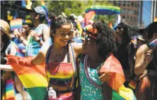  ?? Mason Trinca / Special to The Chronicle ?? Addison Mullins (left) and Georgia Mullins embrace at the parade, a colorful, noisy event that continues for five hours.