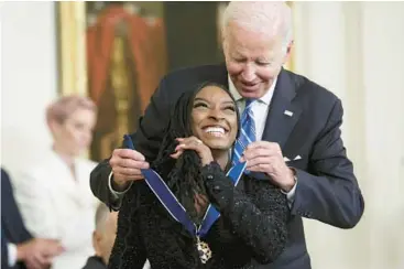  ?? ALEX WONG/GETTY ?? President Joe Biden presents the Presidenti­al Medal of Freedom to Olympic gold medal-winning gymnast Simone Biles on Thursday at the White House. Biles was among 17 to receive the nation’s highest civilian honor. Others included actor Denzel Washington; the late U.S. Sen. John McCain; gun safety advocate Gabby Giffords; soccer icon Megan Rapinoe; and Sandra Lindsay, a New York nurse who was first in the U.S. to receive the COVID-19 vaccine outside clinical trials.