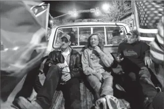  ?? Photos by Dawn Madura, The (Fort Collins) Coloradoan ?? Honk if you love cruising: Stephen Martin, left, Whitney Mart and Zach Bond ride in the bed of a pickup as the flags on either side draw attention on the streets on a Friday night in March in Fort Collins, Colo.