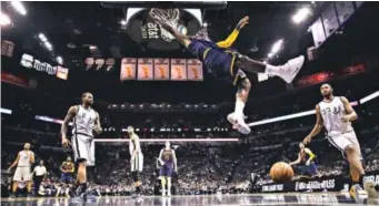  ??  ?? Cavaliers star LeBron James hangs fromthe rim after scoring against the Spurs during the first half of Thursday night’s game in San Antonio. James finished with 22 points. Eric Gay, The Associated Press