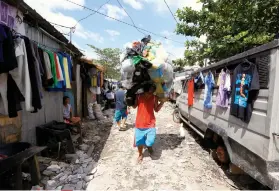  ?? /AP PHOTO/BULLIT MARQUEZ, FILE ?? AN INFORMAL SETTLER in Payatas carries a bale of plastic sheets for recycling. The Supreme Court has prohibited the police from entering the garbage dump community to prevent them from threatenin­g villagers who have accused them of ruthlessly killing...