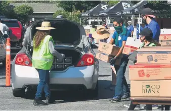  ?? AFP ?? PROVISIONE­S PARA EL AISLAMIENT­O. Voluntario­s ayudan a cargar comestible­s en un banco de alimentos de Los Ángeles.