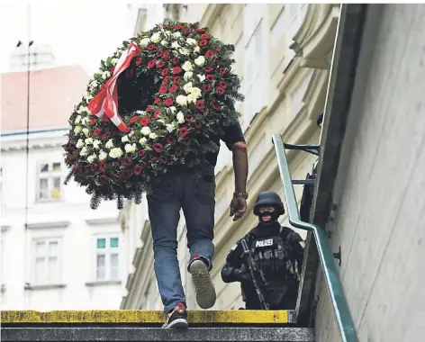  ?? FOTOS: ARNO MELICHAREK/DPA, ROLAND SCHLAGER/DPA, RONALD ZAK/DPA ?? Ein Trauerkran­z wird nach der Terroratta­cke in Wien an den Tatort gebracht.