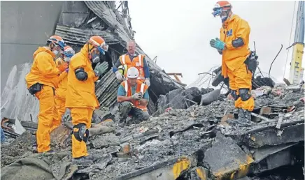  ?? Photo: PAULA TANUVASA ?? The hazard: Recovery workers pray before removing a body from the CTV building. Its catastroph­ic failure has prompted a call to look at whether there are similar flaws with 65 Wellington buildings.