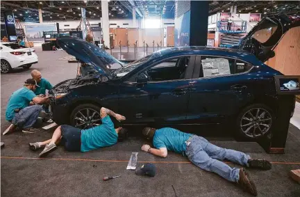  ??  ?? Eagle Management employees work Monday to prepare a Mazda for display at the Houston Auto Show at NRG Center. More than 100,000 people are expected to attend the five-day expo.