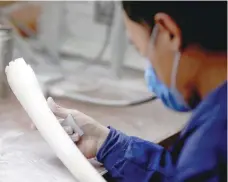  ?? — Reuters file photo ?? A man checks a tusk at an ivory workshop in Beijing.