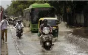  ?? — PRITAM BANDYOPADH­YAY ?? Commuters wade across a waterlogge­d street following pre-monsoon rains at Ashok Nagar in New Delhi on Monday.