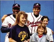  ??  ?? Gretchen Kaney (left), then in middle school, and two friends pose for a photo with Braves stars Ron Gant and David Justice (right) in 1991.