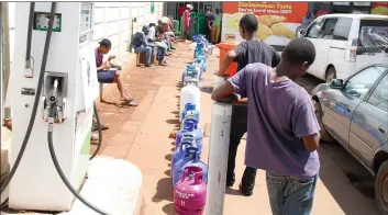  ??  ?? People wait to fill up their gas tanks in Harare yesterday