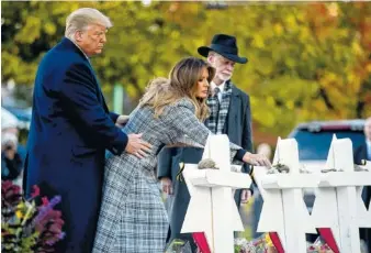  ?? AP PHOTO/ANDREW HARNIK ?? First lady Melania Trump, accompanie­d by President Donald Trump, and Tree of Life Rabbi Jeffrey Myers, puts down a white flower Tuesday at a memorial for those killed at the Tree of Life Synagogue in Pittsburgh.