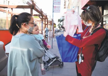  ?? Mallory Moench / The Chronicle ?? Above: Kayla Crenshaw of Epiphany Center, which provides drug treatment to women, shows donated baby clothes to Michele Nguyen and daughter Annabelle; both women graduated from the program and said the city’s system to get into treatment is challengin­g. Below: James Dixon, HealthRigh­t 360’s director of residentia­l services, leads a staff meeting at the treatment program.