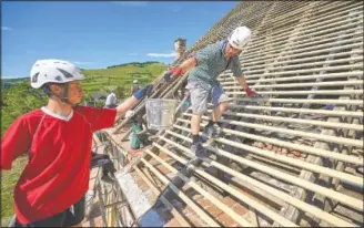  ??  ?? People work on the roof of the 16th-century Brukenthal Castle during repair done by Ambulance for Monuments project volunteers in Micasasa, Romania. Since it launched, Ambulance for Monuments has rescued 55 historical structures — from medieval churches to historic fortificat­ion walls, from old watermills to ancient
UNESCO World Heritage Sites — from descending into ruin.