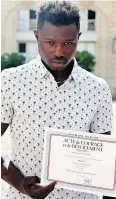  ?? THIBAULT CAMUS / AFP / GETTY IMAGES ?? Mamoudou Gassama from Mali displays a certificat­e of courage and dedication in Paris.