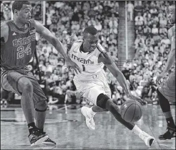  ?? PHOTOS BY CHUCK LIDDY / RALEIGH NEWS & OBSERVER ?? Miami guard Durand Scott races past North Carolina State’s T.J. Warren in their ACC semifinal Saturday. The Hurricanes won 81-71.