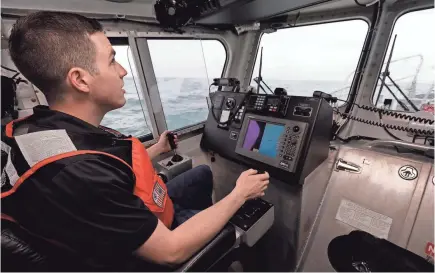  ?? ANDREW COPPLEY/HAROLD HINSON PHOTOGRAPH­Y ?? Alex Bowman piloted a boat while at the Wrightsvil­le Beach Coast Guard Station.