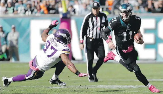  ?? — THE ASSOCIATED PRESS ?? Philadelph­ia Eagles quarterbac­k Carson Wentz runs for a first down past Minnesota Vikings’ Everson Griffen during NFL action Sunday in Philadelph­ia. Wentz led the Eagles to a 21-10 victory over the previously unbeaten Vikings.