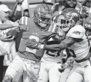  ?? Rogelio V. Solis / Associated Press ?? Ole Miss quarterbac­k Matt Corral, left, pushes off an Arkansas defender in the second half. Corral finished 14-of-21 passing for 287 yards and two touchdowns.