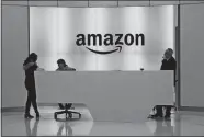  ?? MARK LENNIHAN, AP PHOTO, FILE ?? People stand in the lobby for Amazon offices in New
York. Amazon is ending a charity donation program it ran for a decade in its latest cost-cutting move. In a blog post on Wednesday, the company said the program, called AmazonSmil­e, will shut down by Feb. 20.