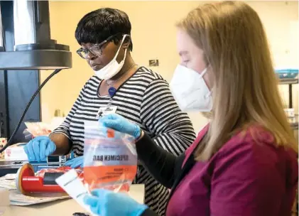  ?? STAFF PHOTO BY TROY STOLT ?? Health care workers Kristen Pennington, right, and Lisa Bledsoe bag up COVID-19 tests provided by the nonprofit organizati­ons Alleo and Cempa at Hospice of Chattanoog­a on Monday.