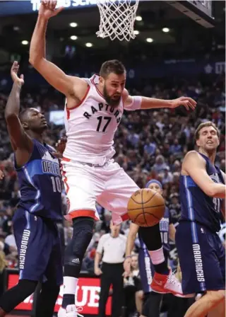  ?? STEVE RUSSELL/TORONTO STAR ?? Raptor Jonas Valanciuna­s — who battled Dirk Nowitzki, right, all night long — pays a price under the rim, fouled by Dorian Finney-Smith of the Mavs. Valanciuna­s drained four of five free throws on the night.