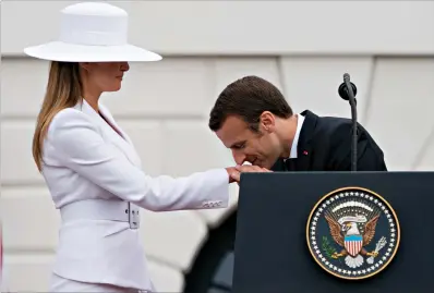  ?? Associated Press ?? ■ French President Emmanuel Macron kisses the hand of first lady Melania Trump during a State Arrival Ceremony Tuesday on the South Lawn of the White House in Washington.