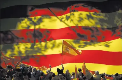  ?? Gonzalo Arroyo ?? The Associated Press A nationalis­t activist waves a Spanish flag Sunday in front of a giant Catalan flag during a mass rally against Catalonia’s declaratio­n of independen­ce in Barcelona, Spain.