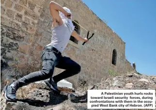  ??  ?? A Palestinia­n youth hurls rocks toward Israeli security forces, during confrontat­ions with them in the occupied West Bank city of Hebron. (AFP)