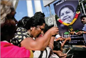  ?? REUTERS ?? Supporters of Tamil Nadu Chief Minister Jayalalith­aa light candles in front of her picture as they pay homage outside her burial site in Chennai on Wednesday.