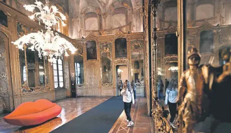  ?? ?? Visitors look at the couch “La Bocca” (The Mouth) presented by Gufram, at the Palazzo Litta as part of the Fuorisalon­e 2024 event, on the eve of the Milan Design Week, in Milan.