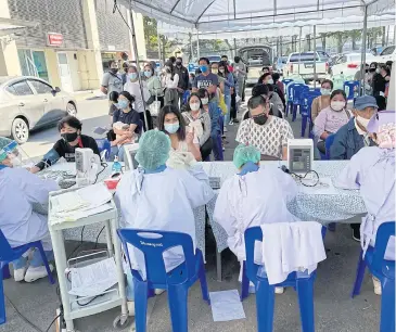  ?? PANUMET TANRAKSA ?? Medical personnel interview people who attended a year-end event in Chiang Mai where a person was found to be infected with Covid-19.