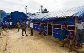  ?? — AFP ?? Safer here: UN officials and Bangladesh police standing guard where Rohingya families were interviewe­d at a refugee camp in Teknaf.