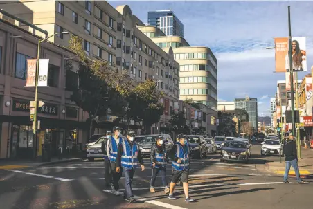  ?? Photos by Stephen Lam / The Chronicle ?? Volunteers in blue vests conduct a safety patrol in Oakland’s Chinatown district after a recent spate of crimes in the area.