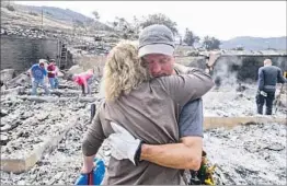  ?? Ringo H.W. Chiu Associated Press ?? CRAIG BOLLESON hugs a friend among the ruins of his home in the SunlandTuj­unga area of Los Angeles. The cause of the wildfire is not yet known.