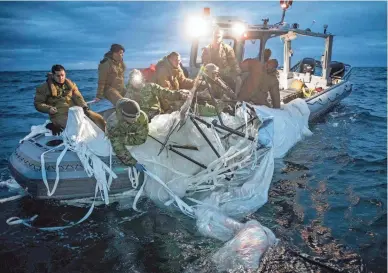  ?? OFFICER 1ST CLASS TYLER THOMPSON/U.S. NAVY VIA GETTY IMAGES ?? U.S. Navy and Coast Guard personnel recover pieces of the downed Chinese balloon on Sunday, the day after it was downed by a fighter aircraft. The Navy has now shifted to an all-underwater search to retrieve the remaining debris.
