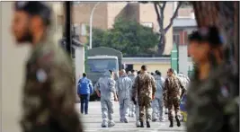  ?? PIC/PTI ?? People wearing protective suits and military personnel walk inside a military complex where 56 Italians evacuated from Wuhan