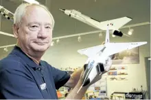  ?? LUKE HENDRY/POSTMEDIA NETWORK ?? Executive director Chris Colton of the National Air Force Museum of Canada holds a model of the Avro Arrow in front of a larger hanging version at the museum Friday in Trenton. A search is underway for larger, flying models of the Arrow submerged in...