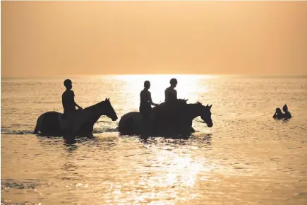  ?? AP PHOTO ?? People ride their horses during a hot summer day at the beach Thursday in De Haan, Belgium. Belgium experience­d code red, extreme heat warning, on Thursday as temperatur­es soared during the second heat wave of the summer.