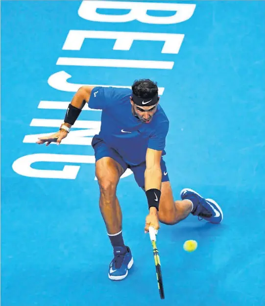  ?? GREG BAKER / AFP ?? Rafael Nadal hace una contorsión para devolver la bola, ayer, en la semifinal del ATP 500 de Pekín, ante Grigor Dimitrov.