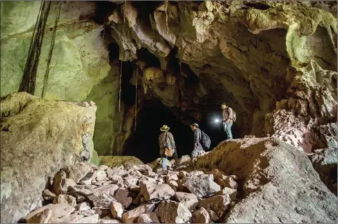  ?? OMAR HAVANA/THE NEW YORK TIMES ?? The chief of the Forestry Associatio­n of Kampong Trach, Ken Sam An (left); Neang Thy, a herpetolog­ist at the Cambodian Ministry of Environmen­t; and Lorn Sokchan, a Cambodian entomology researcher, explore the interior of a cave known as the Bat Cave.