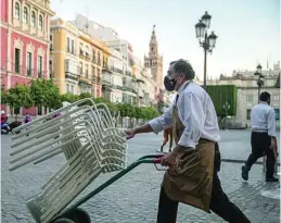  ?? EUROPA PRESS ?? Un camarero recoge el mobiliario de la terraza de un bar en Sevilla