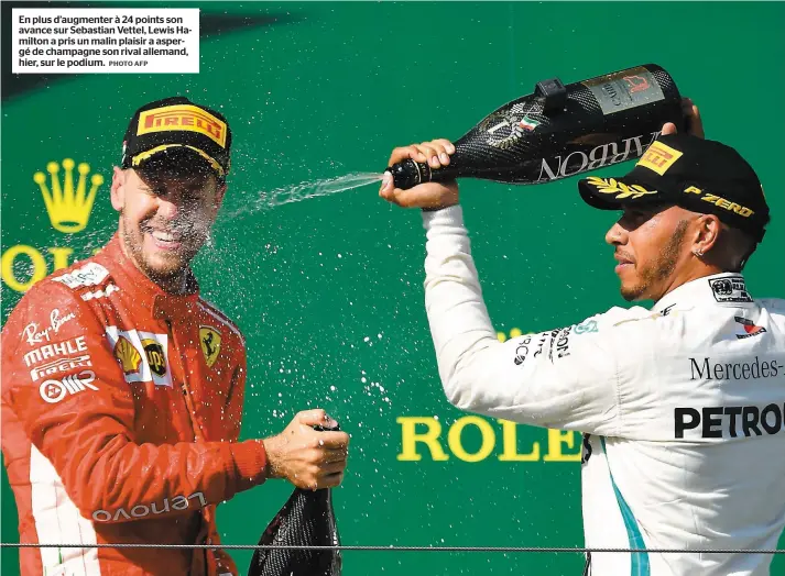  ?? PHOTO AFP ?? En plus d’augmenter à 24 points son avance sur Sebastian Vettel, Lewis Hamilton a pris un malin plaisir a aspergé de champagne son rival allemand, hier, sur le podium.