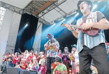  ??  ?? World on a string: Ukulele exponent Shane McAlister leading 100 youngsters in a performanc­e at Porirua Christmas in the Park. He’s expecting a similar-sized contingent for a workshop at tomorrow’s Festival of the Elements.