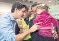  ?? NATHAN DENETTE THE CANADIAN PRESS FILE PHOTO ?? Prime Minister Justin Trudeau greets a young Syrian refugee and her father upon their arrival at Pearson airport in December 2015.