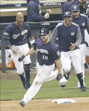  ??  ?? Mike Moustakas rounds first after driving in the winning run with a single in the 10th inning to give the Brewers a 3-2 win against the Rockies Thursday in Game 1 of their NLDS in Milwaukee.